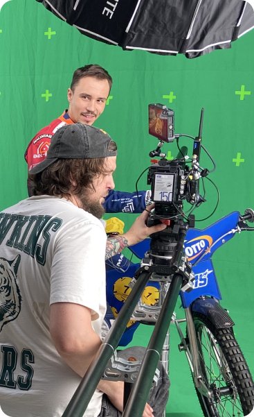 Operator kamery filmujący Dominika Kuberę na tle green screenu.